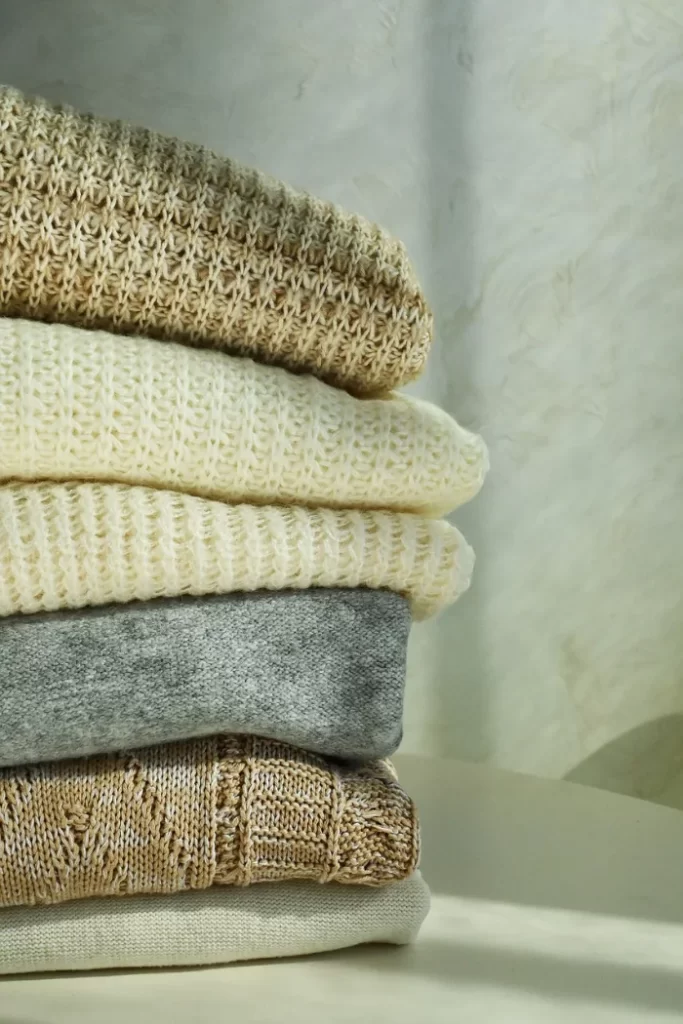 Sloupec poskládaných designových svetrů